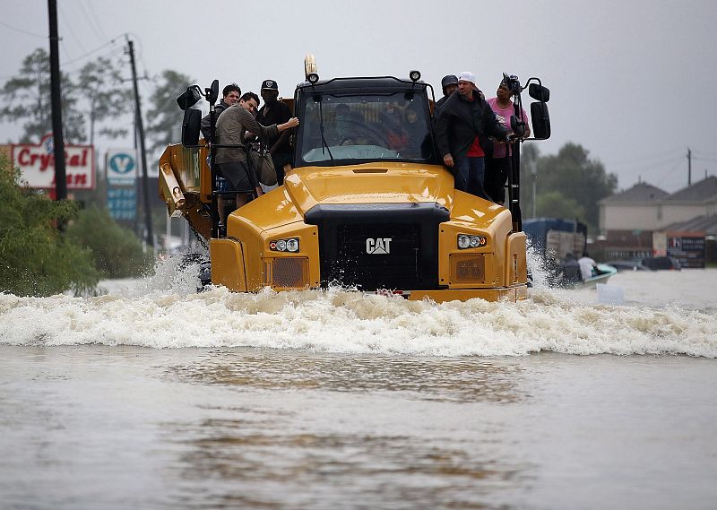Grupo de gente subida a maquinaria de construcción durante las inundaciones provocadas por el huracán Harvey.