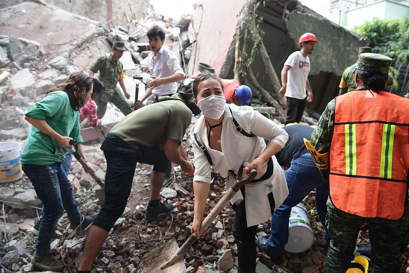 Voluntarios y miembros de los equipos de emergencias buscan a posibles supervivientes en la capital mexicana