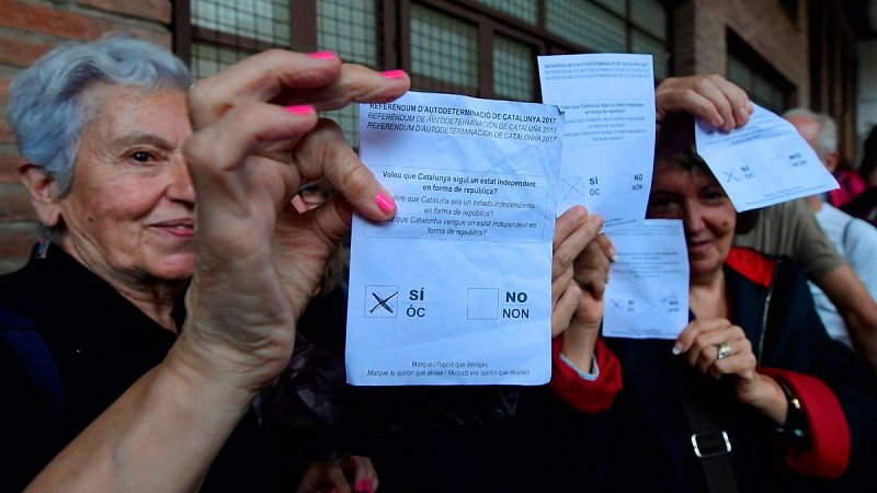 Varias personas muestran las papeletas de votación en un colegio en Barcelona