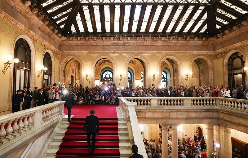 Es el momento en el que Carles Puigdemont sube las escaleras del Parlamento de Cataluña rodeado de prensa