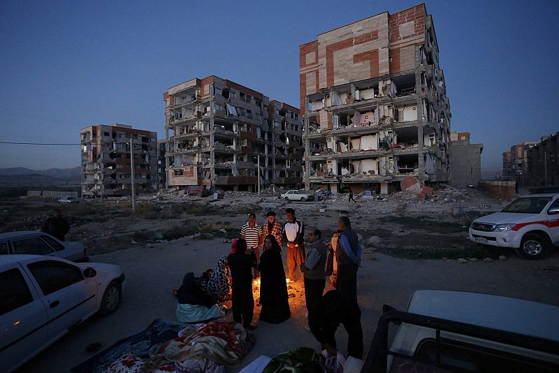 Afectados por el terremoto en la ciudad iraní de Sarpul Zahab se calientan en un fuego