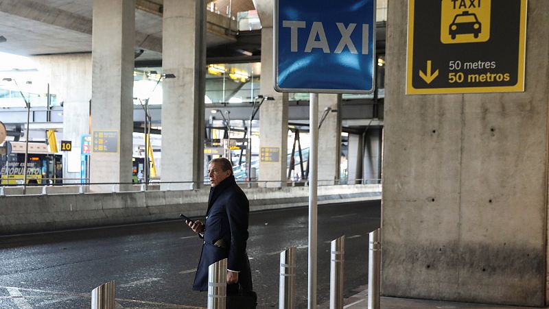 A man looks at his mobile phone while standing at an empty airport taxi stop during a strike by taxi drivers to protest what they say is unfair competition from new car sharing companies such as Uber and Cabify, at the airport in Madrid