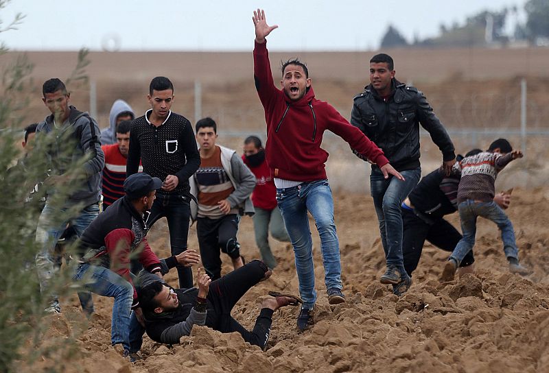 Un hombre pide ayuda para atender a un herido de bala en los enfrentamientos entre palestinos e israelíes en la frontera de Gaza