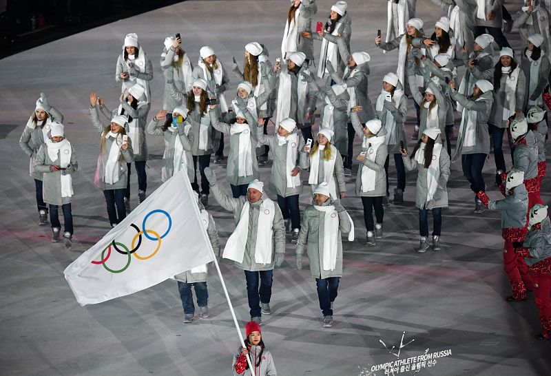 Los atletas rusos a los que les han permitido participar en los Juegos desfilan bajo la bandera olímpica, portada por una voluntaria.