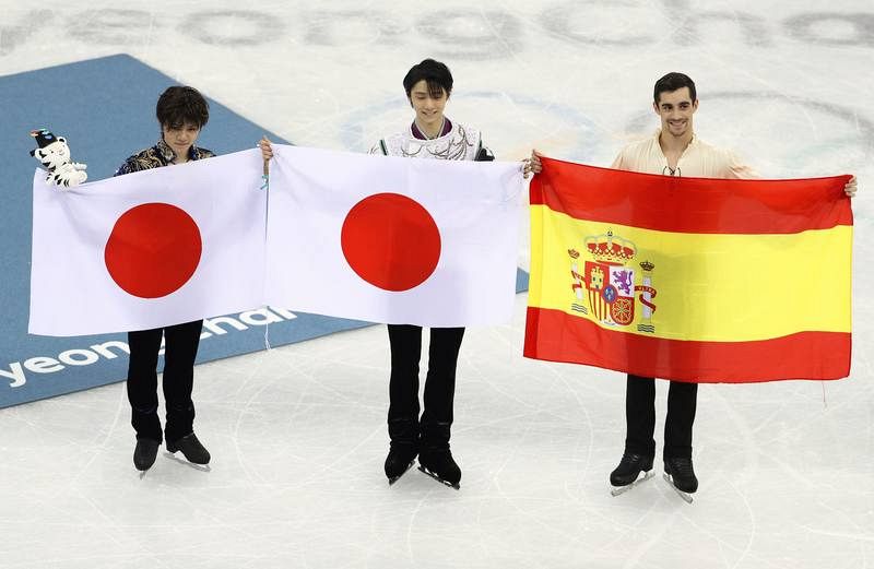 De izquierda a derecha, los japoneses Uno (segundo), Hanyu (primero) y el español Fernández posan con sus banderas tras la final.