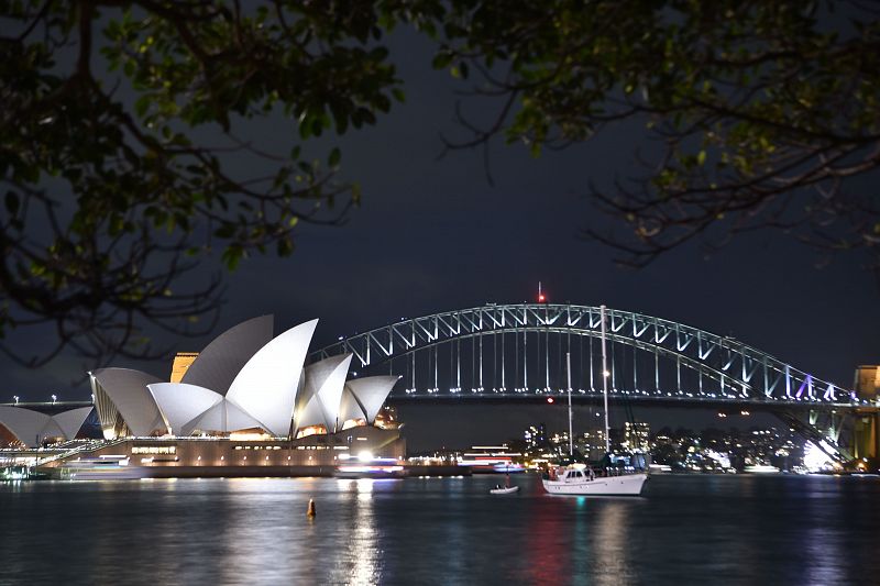 El Puente de la Bahía de Sídney y la Ópera momentos antes de que se apaguen las luces que iluminan ambos iconos de la ciudad australiana