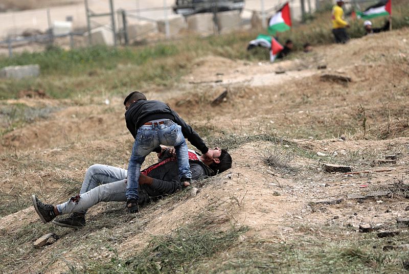 Un palestino ayuda a un compañero herido durante los enfrentamientos con soldados israelíes en el este de Beit Hanun, norte de la Franja de Gaza