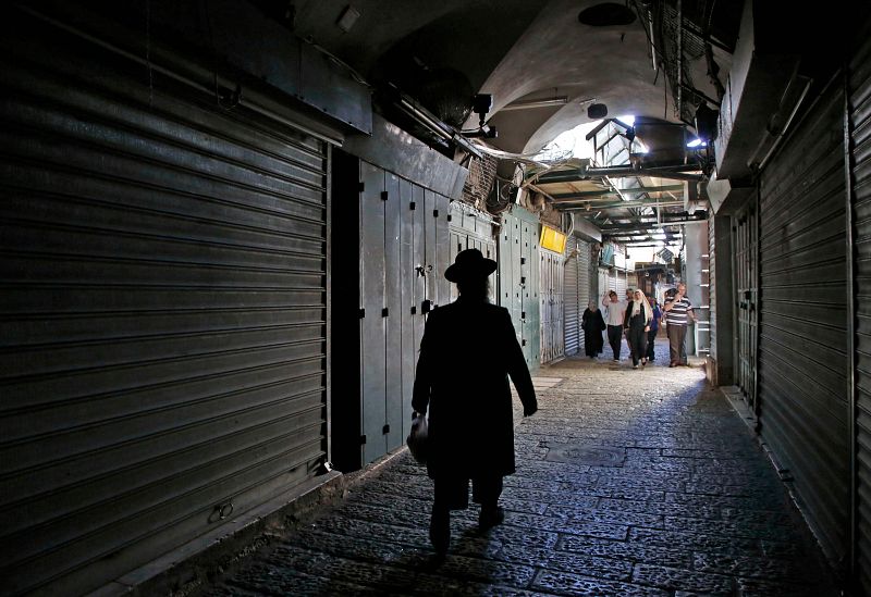 Judíos y musulmanes pasean entre las tiendas cerradas de la Ciudad Vieja de Jerusalén