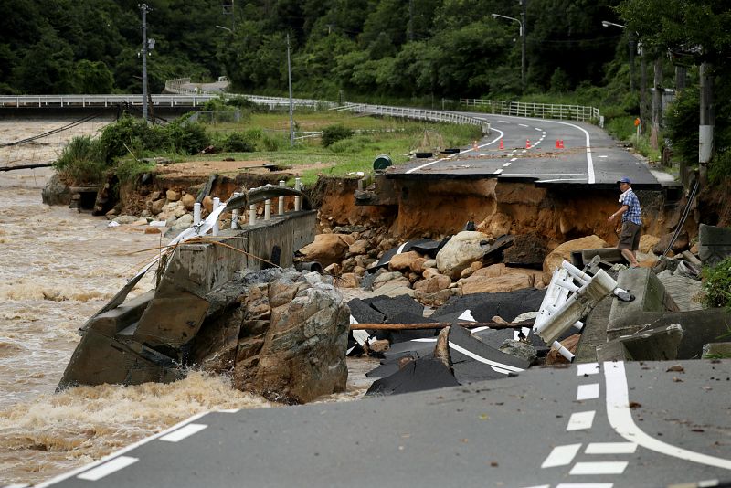 Un hombre sobre una carretera destrozada por las lluvias en Higashihiroshima