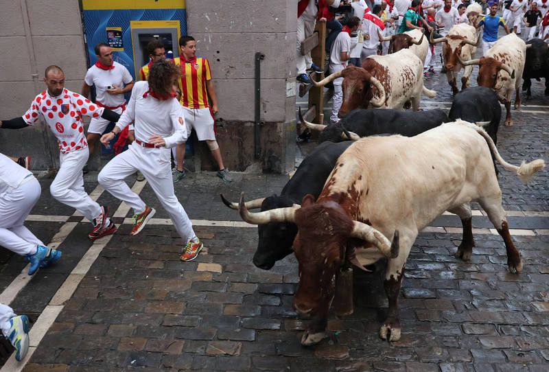 Revellers sprint in front of bulls during the sixth running of the bulls of the San Fermin festival in Pamplona