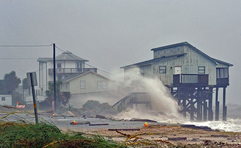 Una ola embate contra una vivienda en la playa de Alligator Point