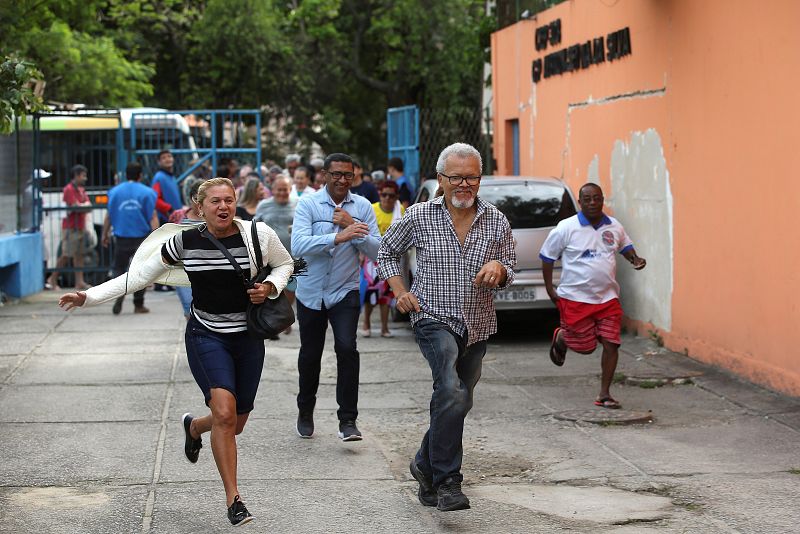 Votantes entran corriendo en el colegio electoral en la Favela de Rocinha, en Río de Janeiro