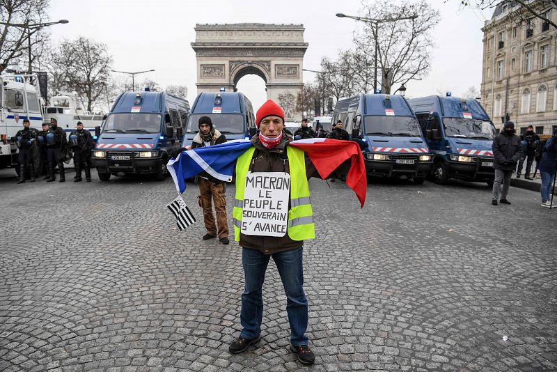 Un manifestante porta una pancarta que reza "Macron el pueblo soberano avanza"