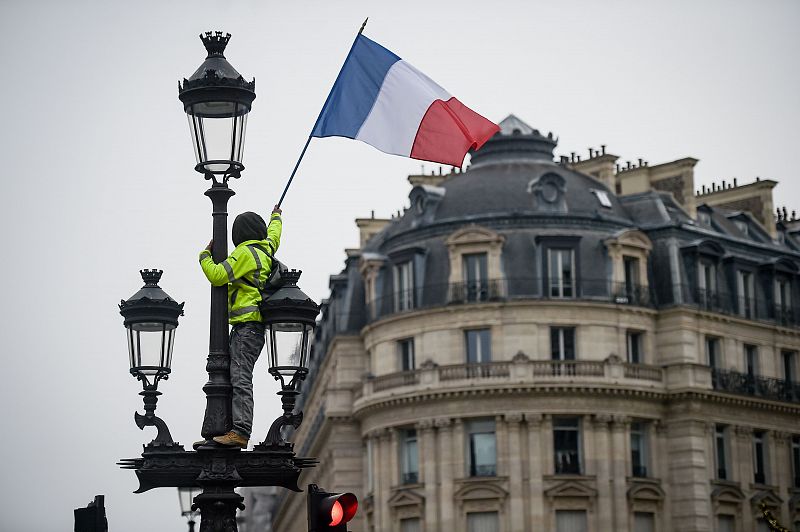 Un manifestante ondea la bandera de Francia encaramado a una farola