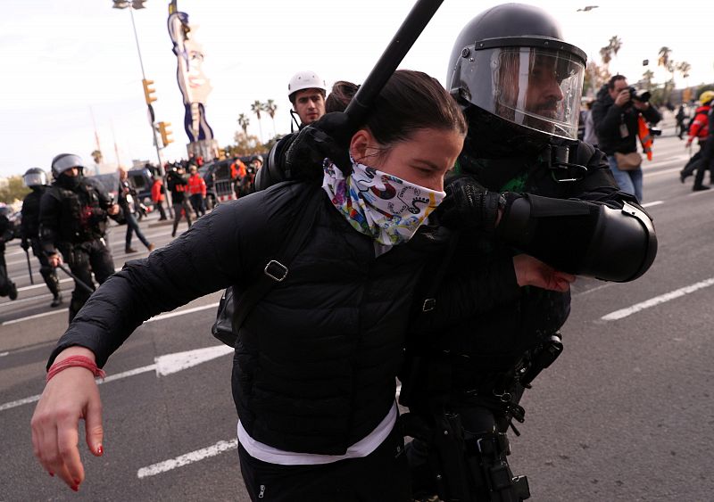 Un policía detiene a una manifestante durante la protestas  en el primer aniversario de las elecciones catalanas convocadas por el Gobierno de Mariano Rajoy con el artículo 155 de la Constitución
