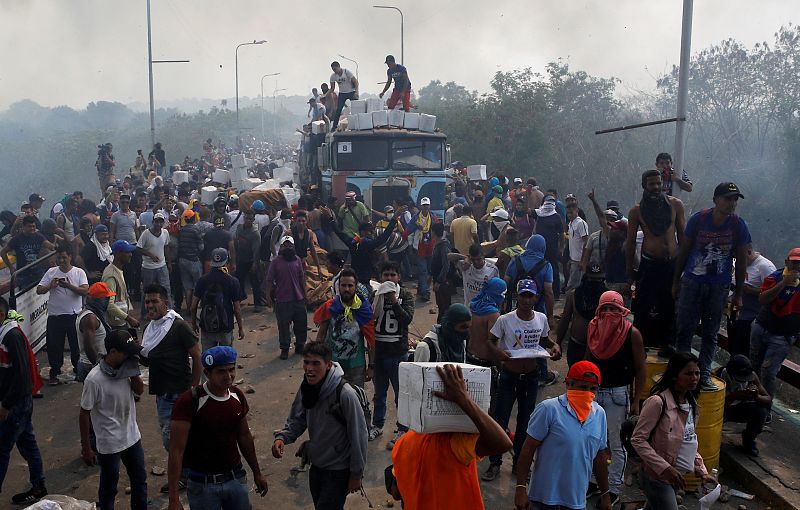 Seguidores de Guaidó descargan ayuda humanitaria de uno de los camiones que ha ardido en el puente Francisco de Paula Santander