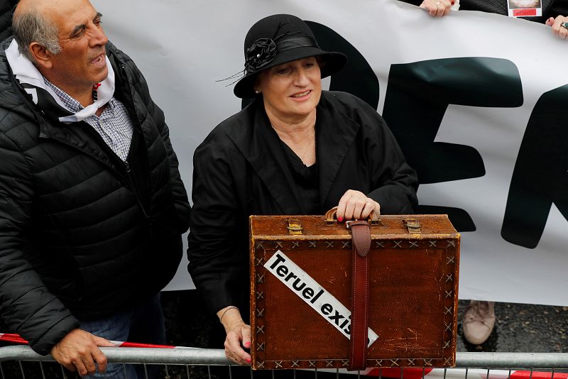 Una mujer con una maleta antigua en la manifestación