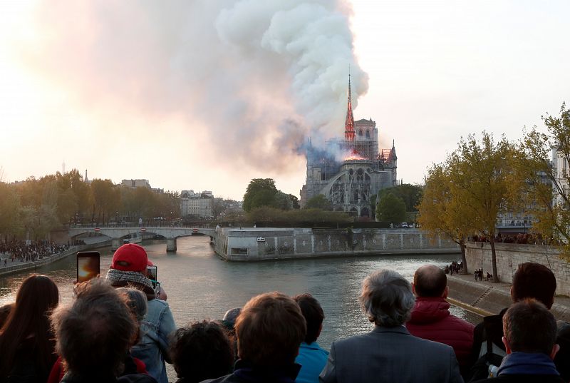 La gente mira desde un puente mientras el humo se eleva desde la catedral durante el incendio en París.
