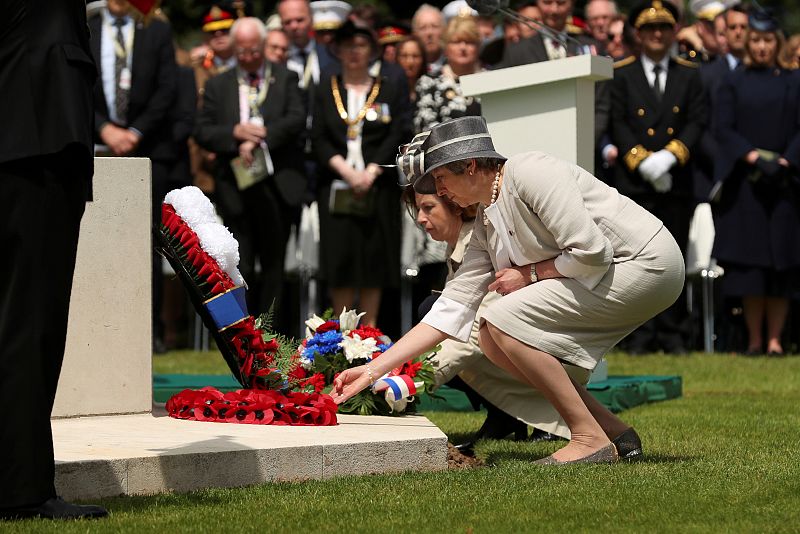 La primera ministra británica, Teresa May, y la ministra francesa de Defensa, Florence Parly, depositan flores durante el homenaje a los caídos en la batalla de Normandía.