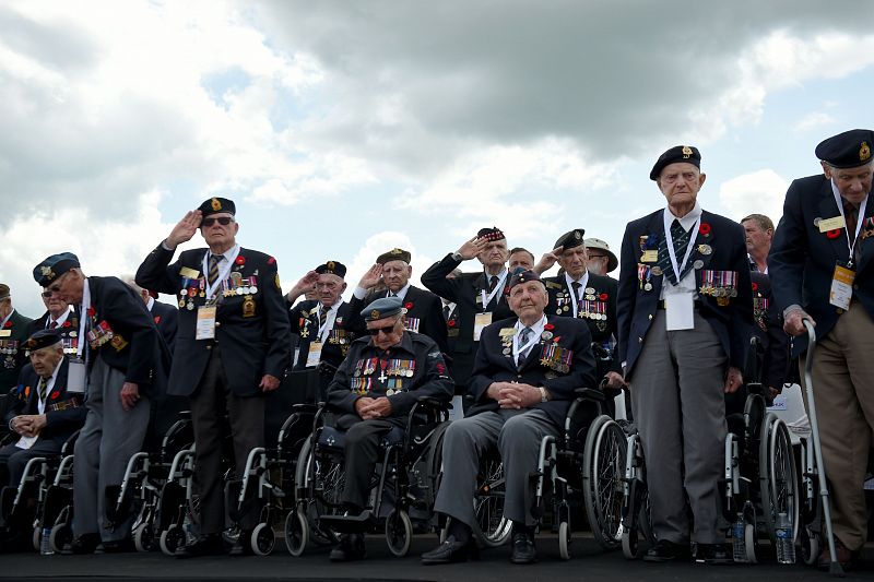 Los veteranos de guerra canadienses se ponen en pie durante el Himno Nacional en la ceremonia internacional celebrada en la playa de Juno, Normandía.