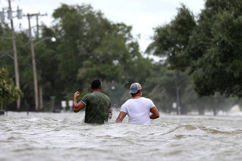 Dos personas caminan por una calle inundada en Mandeville