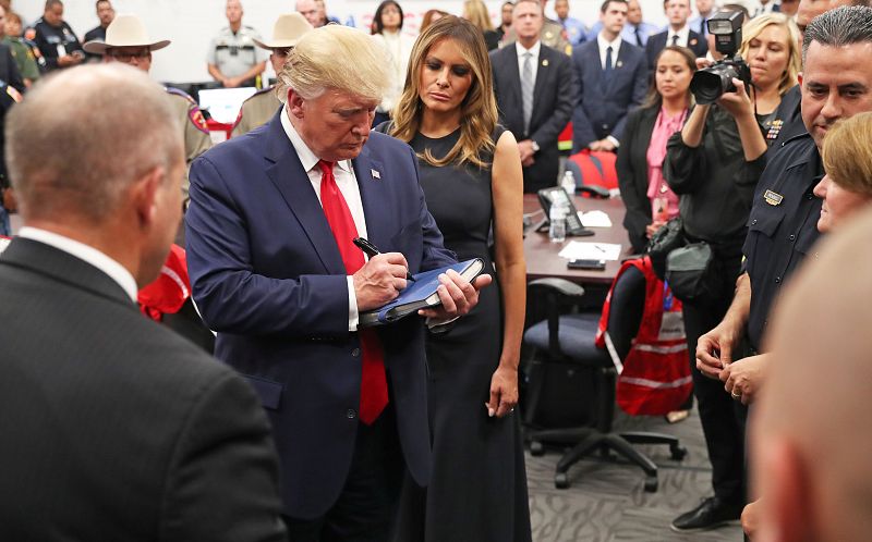 La primera dama, Melania Trump, observa como el presidente estadounidense, Donald Trump, firma un libro después de hablar con agentes de la ley durante su visita a El Paso tras el tiroteo