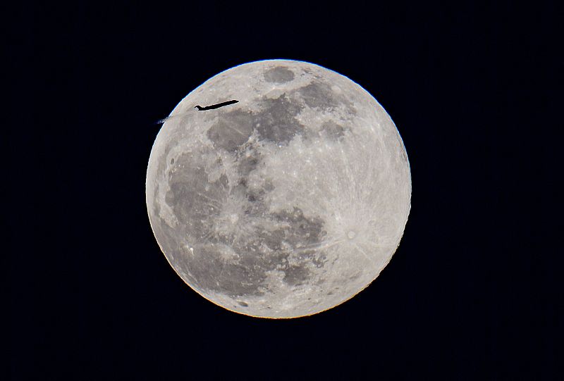 Un avión vuela sobre la superluna rosa de abril en Manhattan, New York.