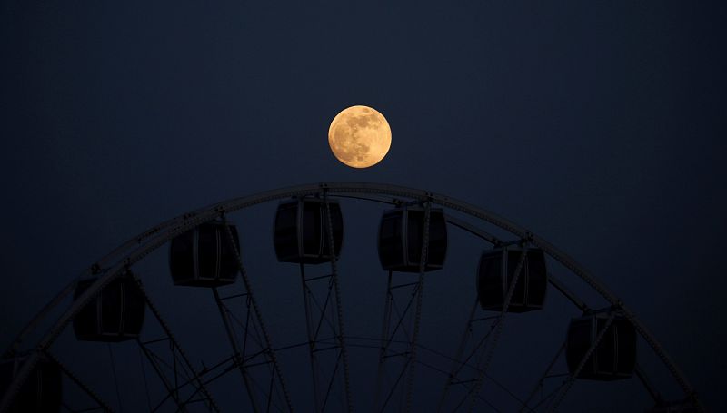 La Luna llena de mayo este miércoles sobre las cabinas de una noria de feria en Córdoba. 