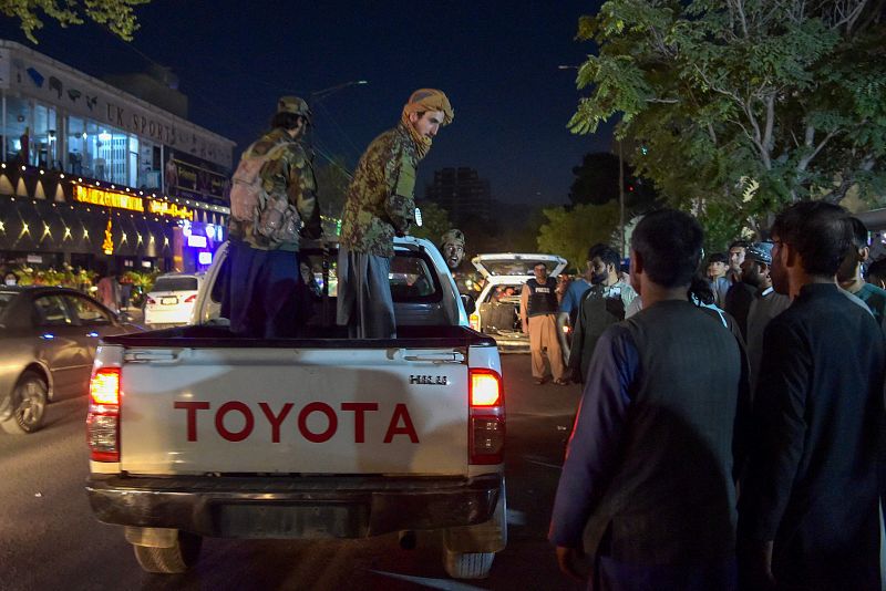 Varios talibanes circulan en un vehículo a las puertas de un hospital, mientras algunos voluntarios trasladan heridos.