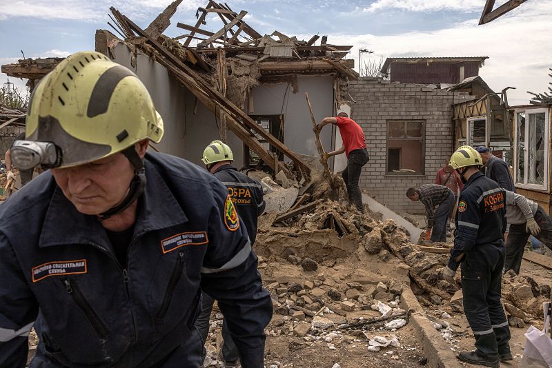 Residentes locales y miembros del servicio de emergencia ucraniano retiran los escombros de una casa dañada tras un ataque con cohetes en Zaporizhzhia, Ucrania. 