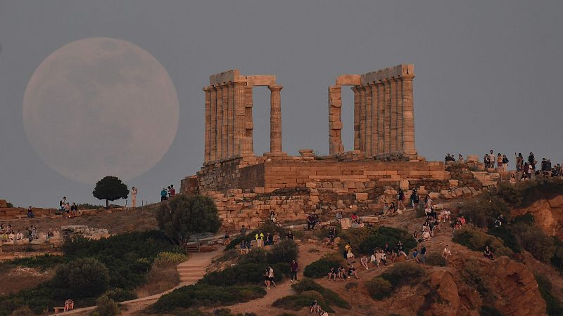 Un grupo de personas observa la salida de la luna por el Templo de Poseidón en Sunio, a unos 70 kilómetros al sur de Atenas.