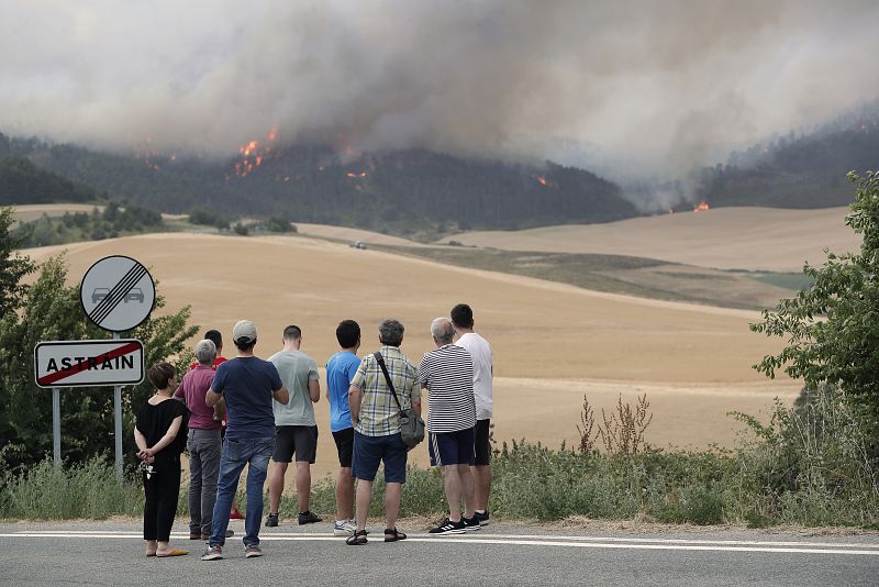 Varias personas miran un incendio desde las afueras de la localidad de Astráin
