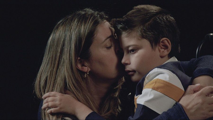 madre besa a su hijo sobre fondo negro