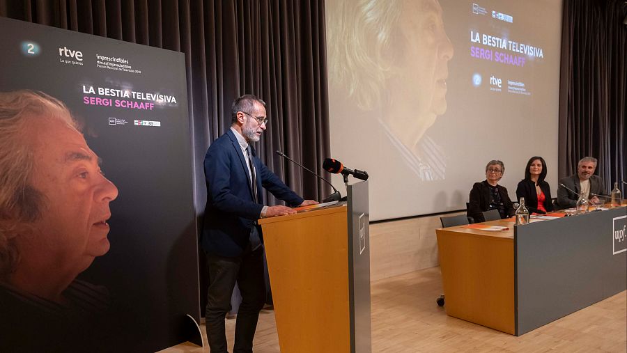 Esteve Crespo, a l'atril i de fons Pilar Ruiz, Judith Fernández i Marcos Hernández asseguts a la taula