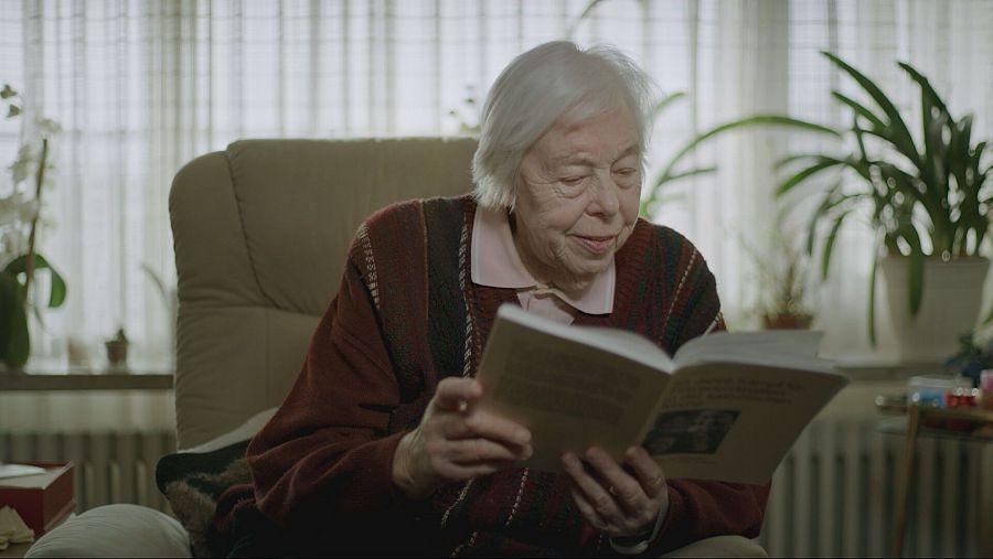 Una mujer leyendo un libro sentada en un sofá de un salón.