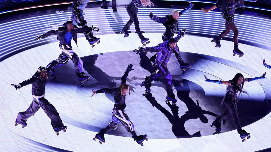 El cantante Usher patinando junto a varios bailarines durante su actuación en la Super Bowl