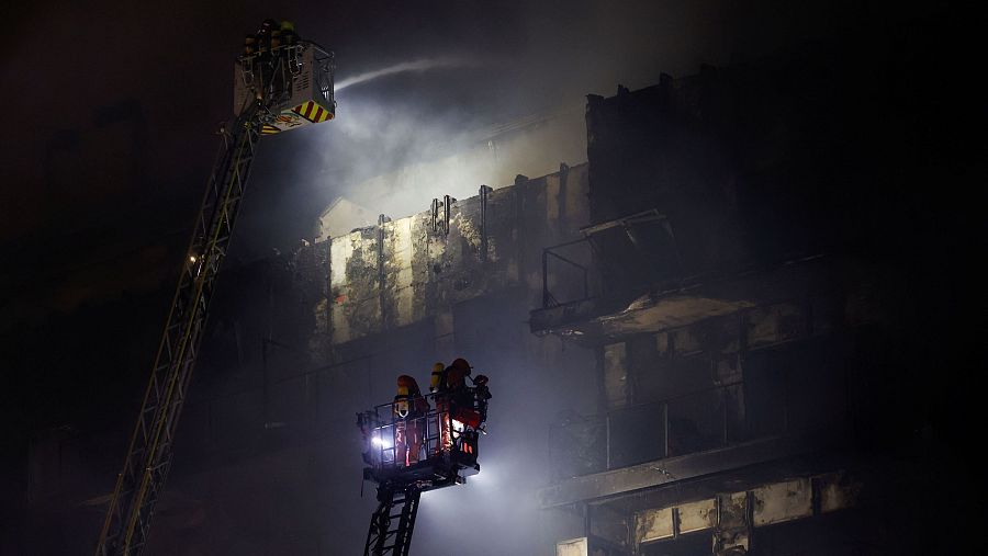 Los bomberos enfrían la fachada del edificio calcinado
