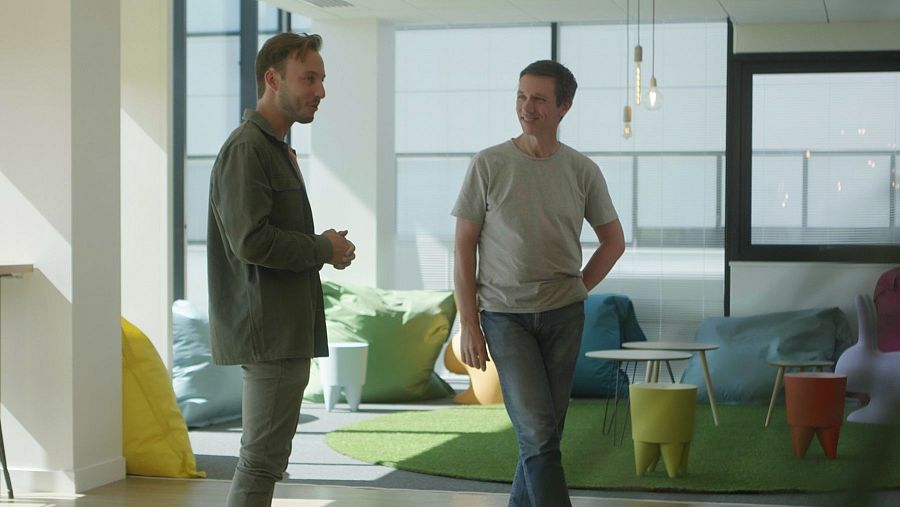 Dos hombres de pie hablan en un despacho de oficina