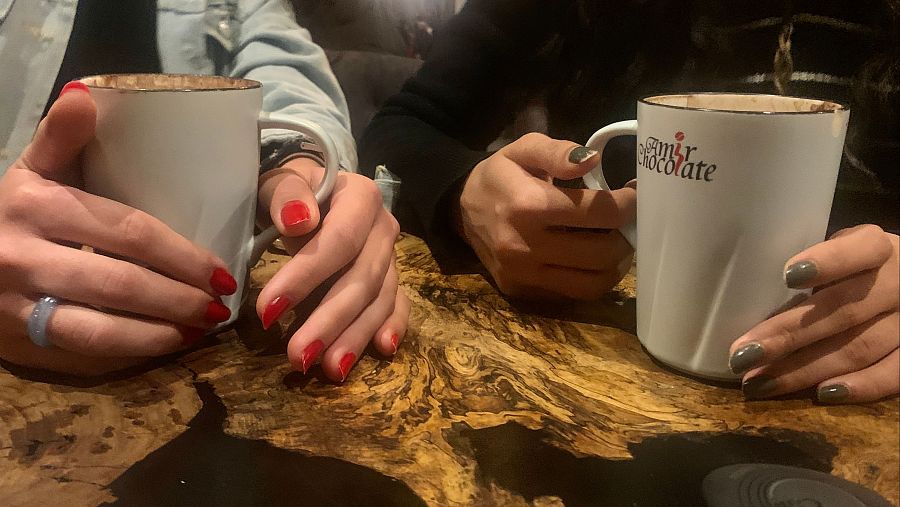 Neda y Nur tomando un chocolate caliente en la cafetería de la escuela de artes