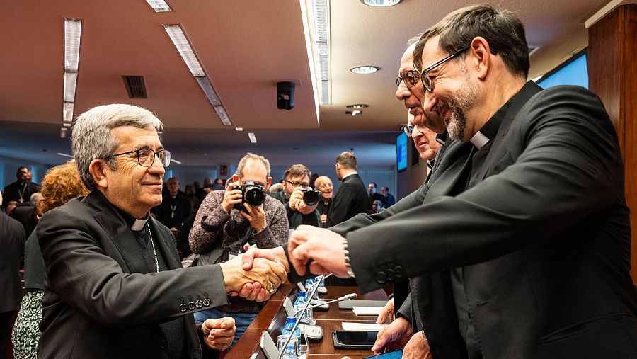 Dos obispos se saludan estrechando sus manos sonrientes.