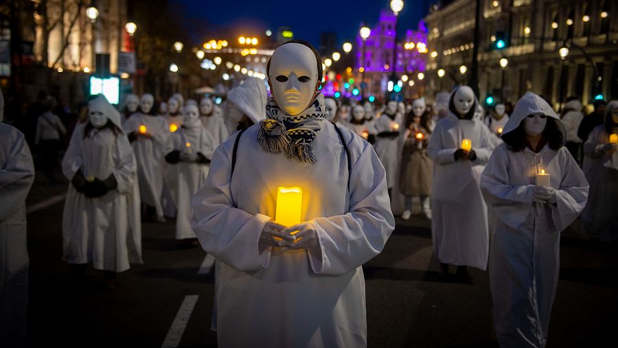 Un grupo de mujeres atraviesan la Gran Vía vestidas de blanco, con máscaras y velas