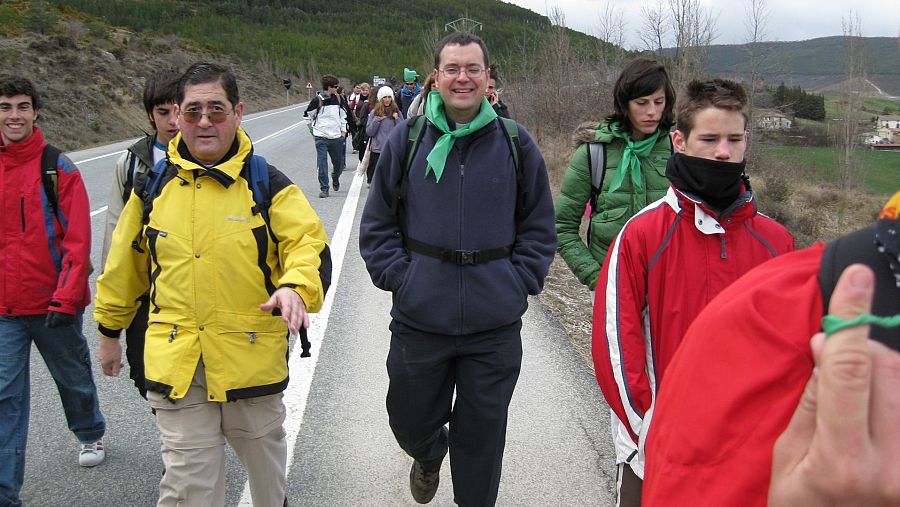 Un grupo de personas con pañuelos verdes al cuello caminando por la carretera