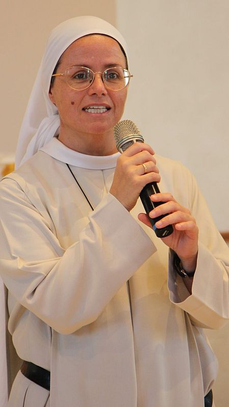 Una monja con velo y un micrófono en las manos.