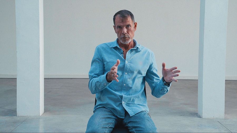 Hombre con barba blanca sentado en silla.