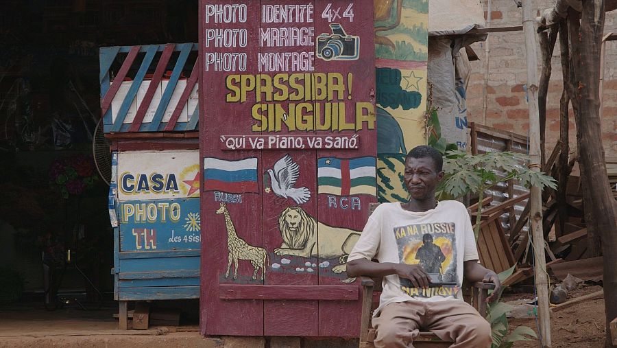 Hombre centroafricano sentado delante de un estudio de fotos.