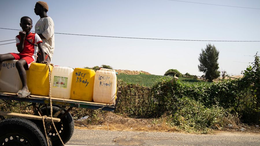 Un hombre y un niño transportando bidones en una carretera de Senegal