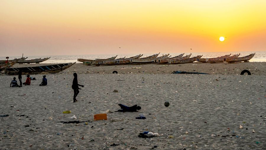 Niños jugando frente a varios cayucos en una playa de Saint Louis