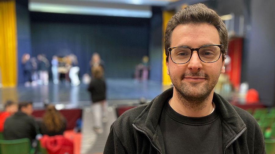 Retrato de un hombre con gafas y escenario difuminado al fondo.