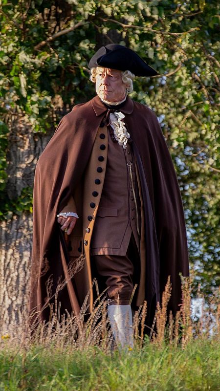 Hombre con capa, bastón y vestidos del siglo XVIII pasea por el campo