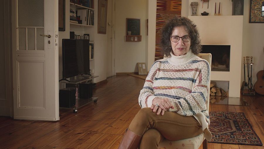 Mujer con gafas y pelo rizado sentada en un comedor